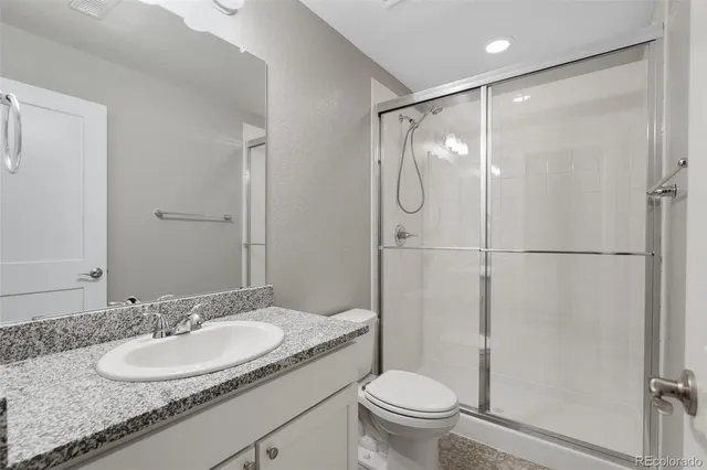 a bathroom with a granite countertop sink toilet and shower