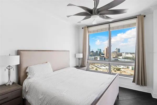 a bedroom with a large bed and a large window with view of balcony