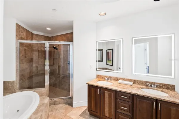 a bathroom with a double vanity sink and mirror with bathtub