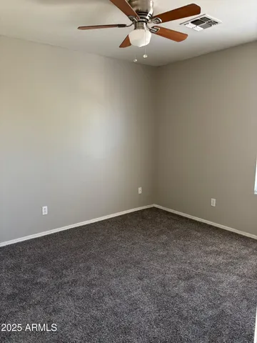 an empty room with a ceiling fan and carpet
