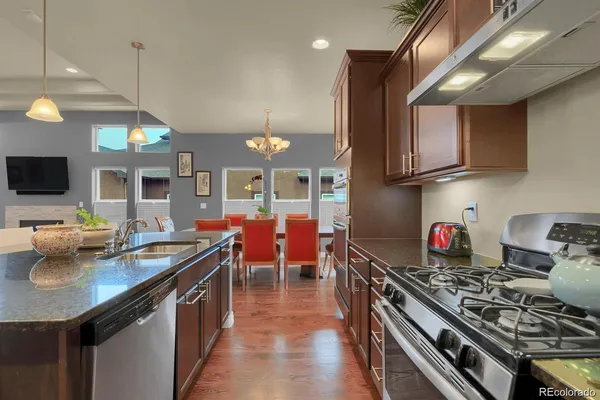 a kitchen that has a lot of stainless steel appliances a stove and a wooden floor