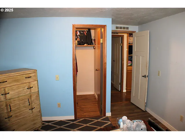a view of a hallway with wooden floor and cabinet