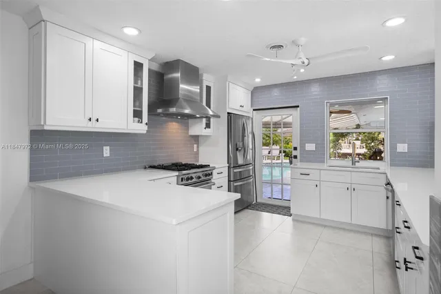 a kitchen that has a lot of white cabinets and stainless steel appliances