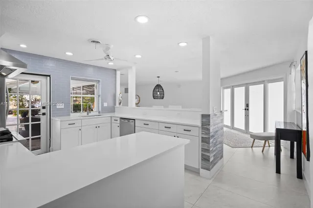 a large white kitchen with furniture a large window and stainless steel appliances