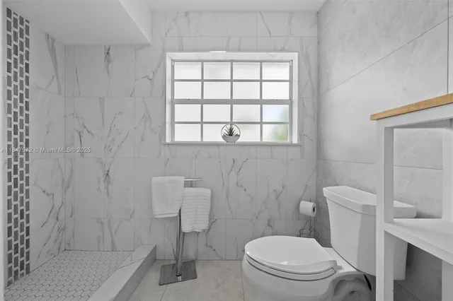 a white toilet sitting next to a bathroom sink and vanity