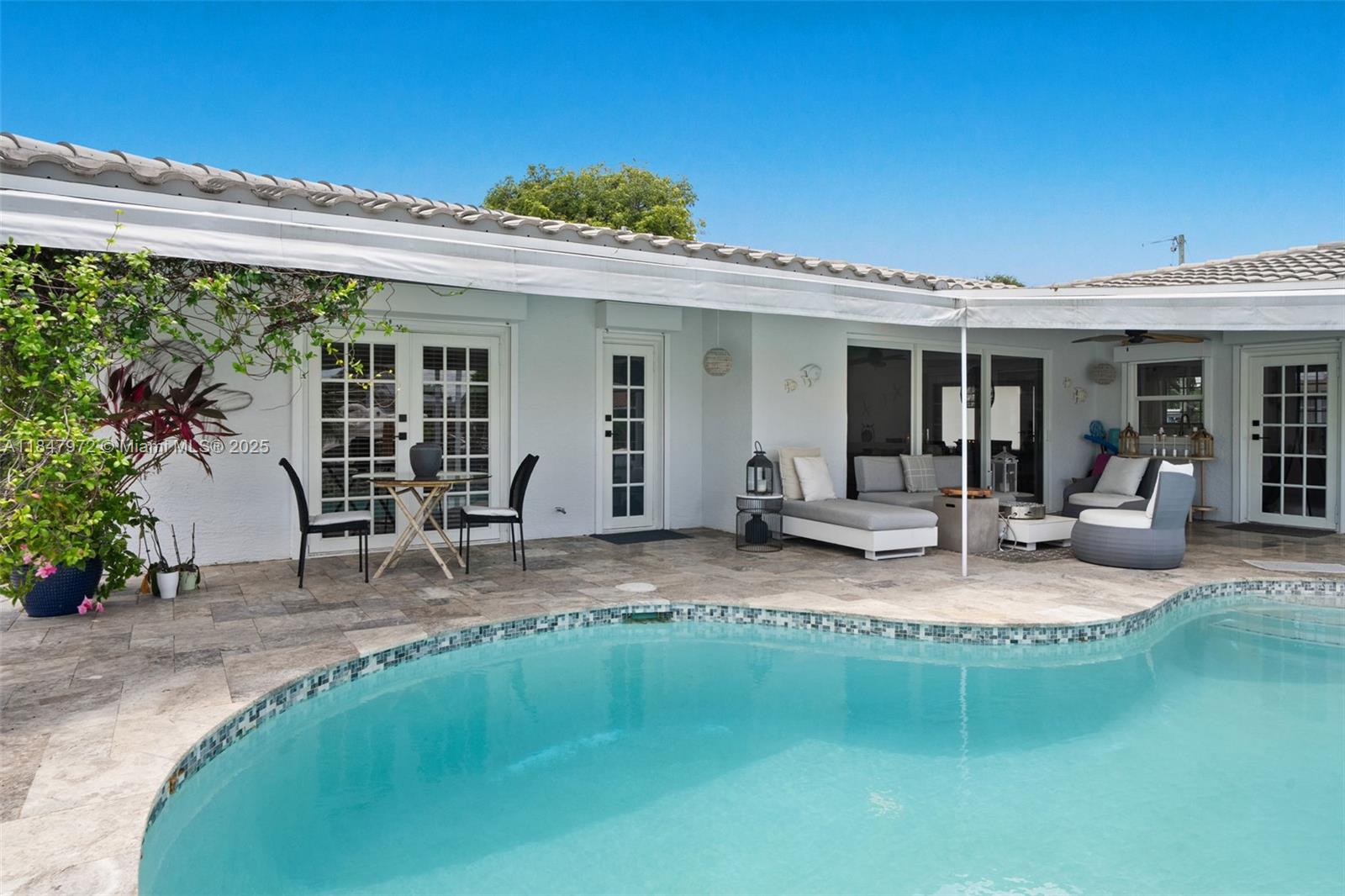2681 Northeast 9th Court Pompano Beach, FL 33062 - Photo 39 of 58 a view of a patio with table and chairs potted plants and floor to ceiling window