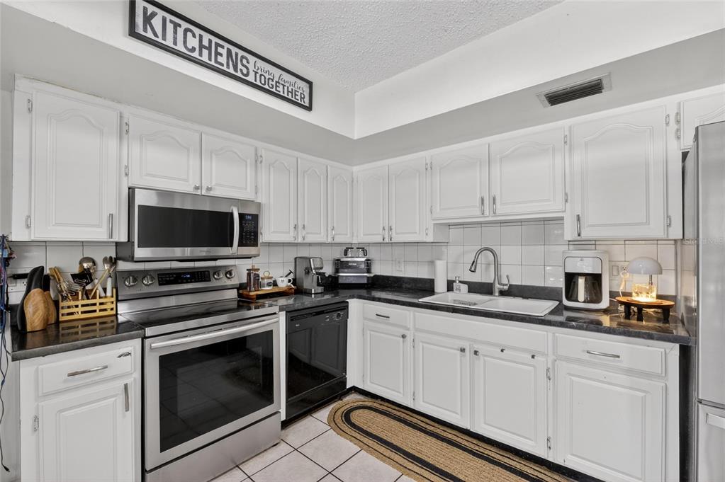 6609 Jennifer Drive Temple Terrace, FL 33617 - Photo 18 of 49 a kitchen with stainless steel appliances granite countertop a sink a stove a microwave and cabinets