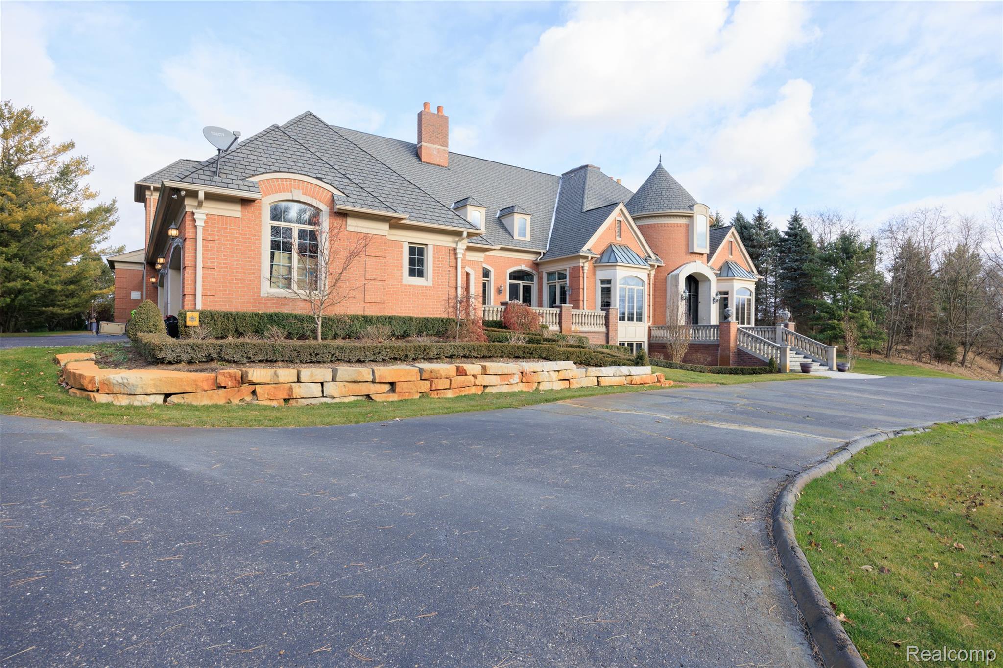 5165 Abbey Drive Rochester, MI 48306 - Photo 58 of 66 Brick facade residence with a turret entry, multiple dormer windows, a grand stone staircase, and a tiered stone retaining wall