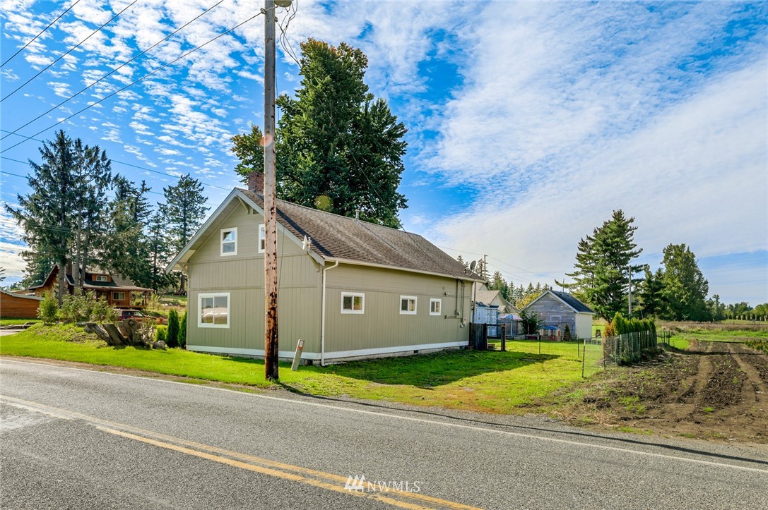 2890 East Badger Road Everson, WA 98247 - Photo 1 of 38 a view of a white house with a small yard and large trees