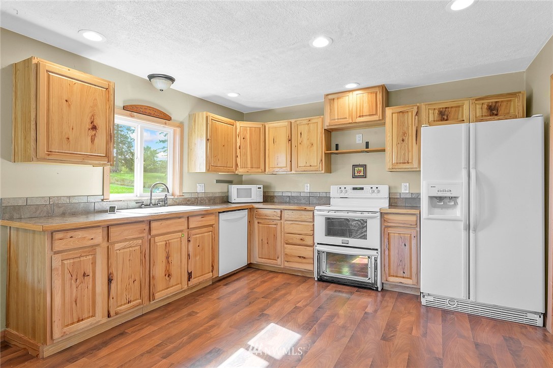2890 East Badger Road Everson, WA 98247 - Photo 17 of 38 a kitchen with granite countertop a refrigerator and white cabinets