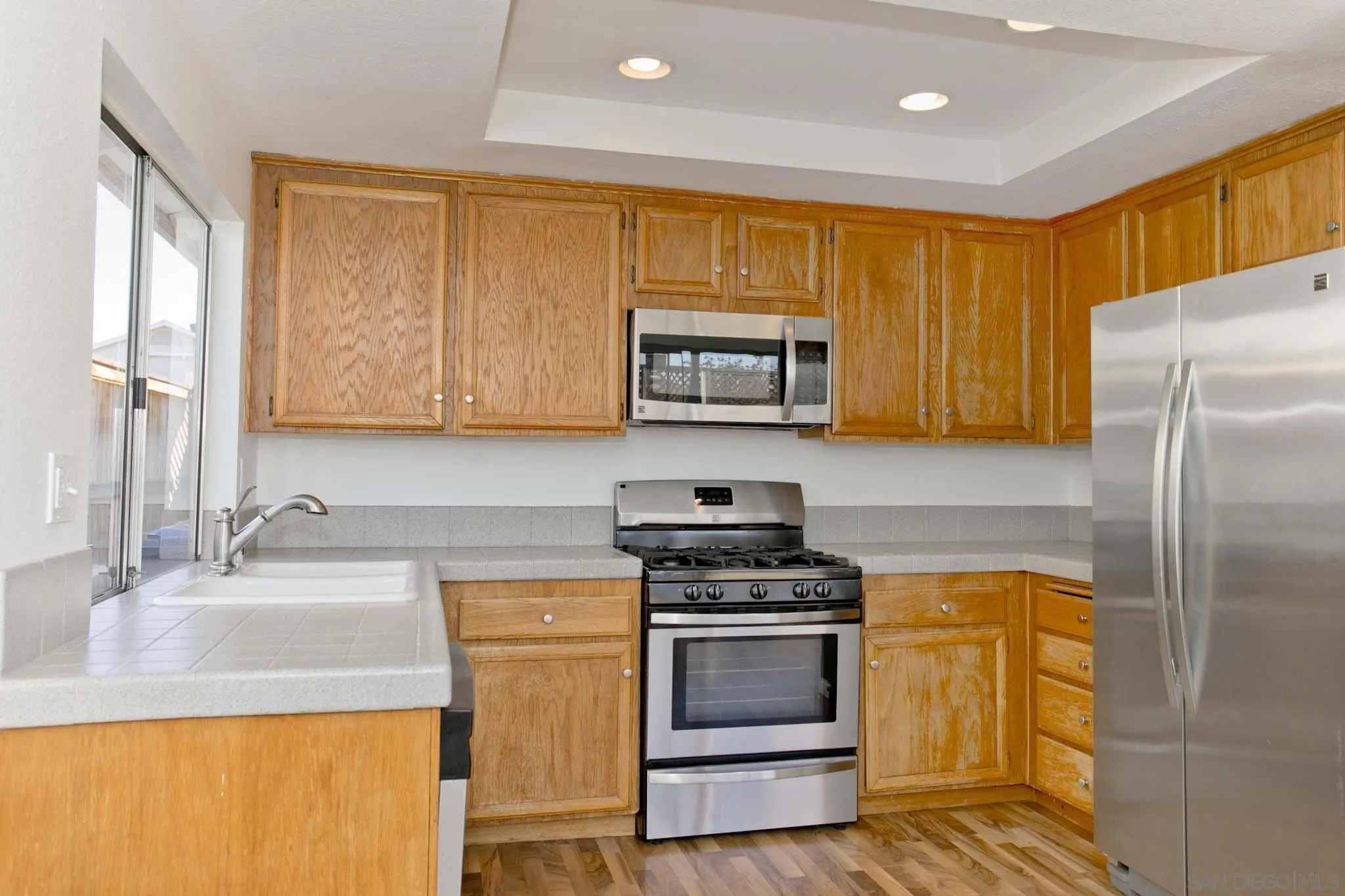10076 West Glendon Circle Santee, CA 92071 - Photo 10 of 35 a kitchen with stainless steel appliances granite countertop a stove a sink dishwasher and a refrigerator with wooden cabinets