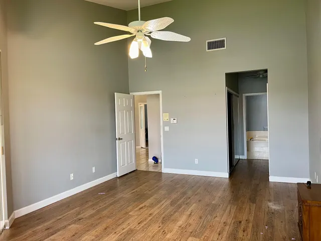 an empty room with wooden floor fan and windows