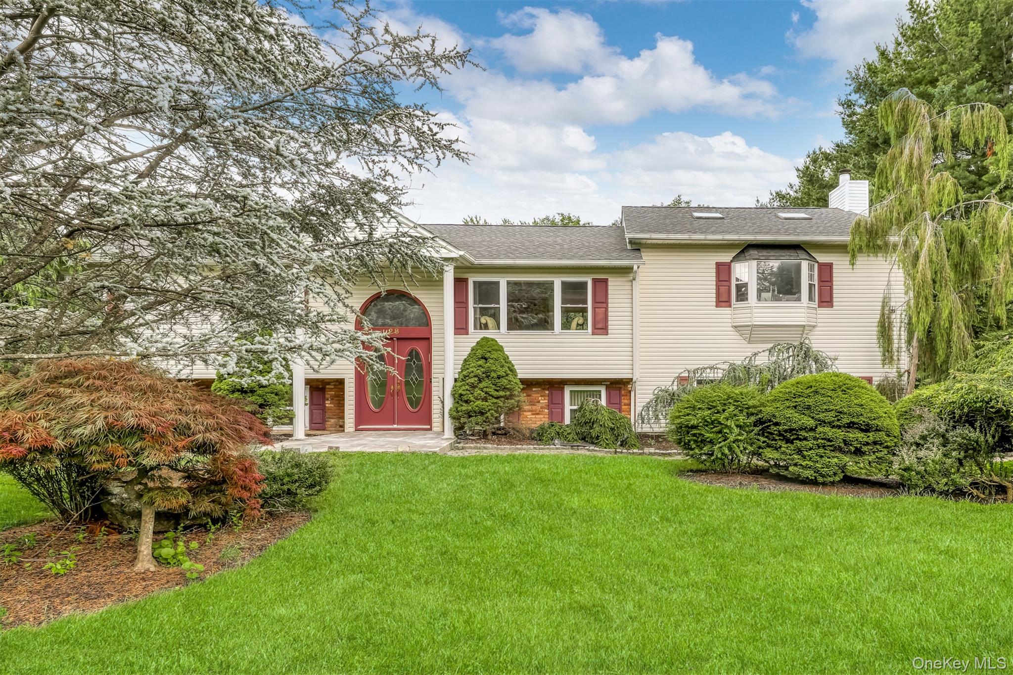 Split foyer home with a front yard, a chimney, and a shingled roof