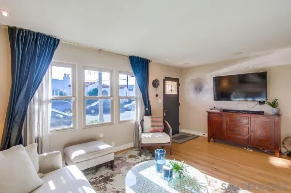 a living room with furniture a flat screen tv and a floor to ceiling window
