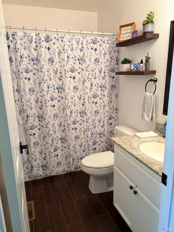 a bathroom with a granite countertop sink and a toilet