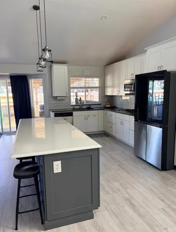 a kitchen with stainless steel appliances a sink a stove a refrigerator cabinets and a dining table