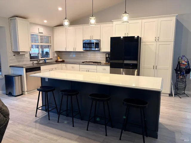 a kitchen with stainless steel appliances granite countertop a table chairs sink refrigerator and microwave