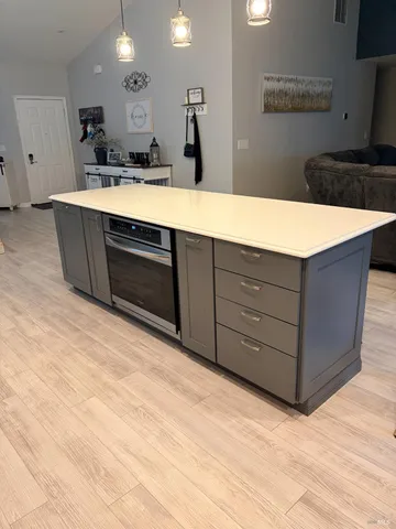 a living room with stainless steel appliances kitchen island sink and cabinets