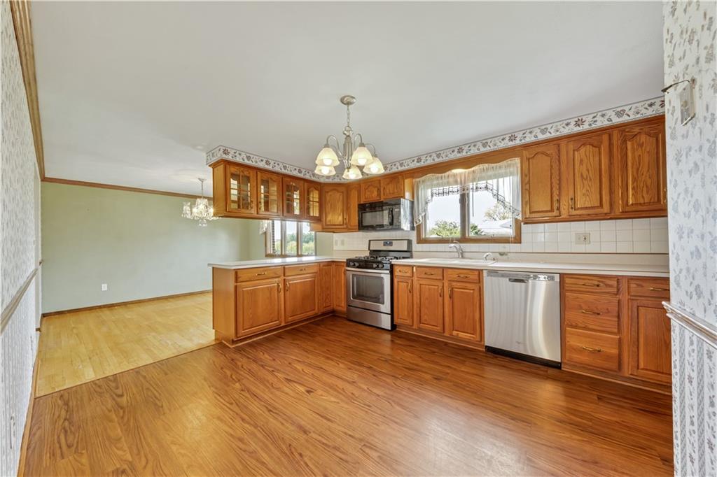 1004 Fiddleback Drive McKees Rocks, PA 15136 - Photo 8 of 25 a kitchen with granite countertop wooden floors and white cabinets