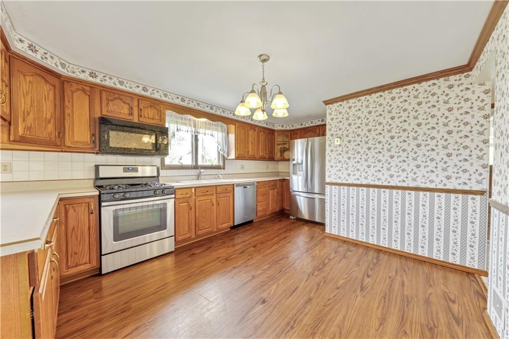 1004 Fiddleback Drive McKees Rocks, PA 15136 - Photo 9 of 25 a kitchen with stainless steel appliances a stove top oven a sink dishwasher and a microwave oven on the wooden floor