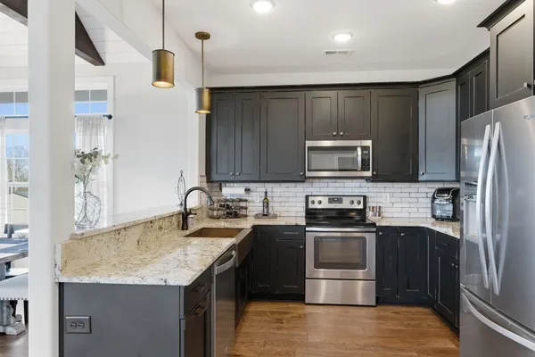 a kitchen with a dining table wooden floor and stainless steel appliances