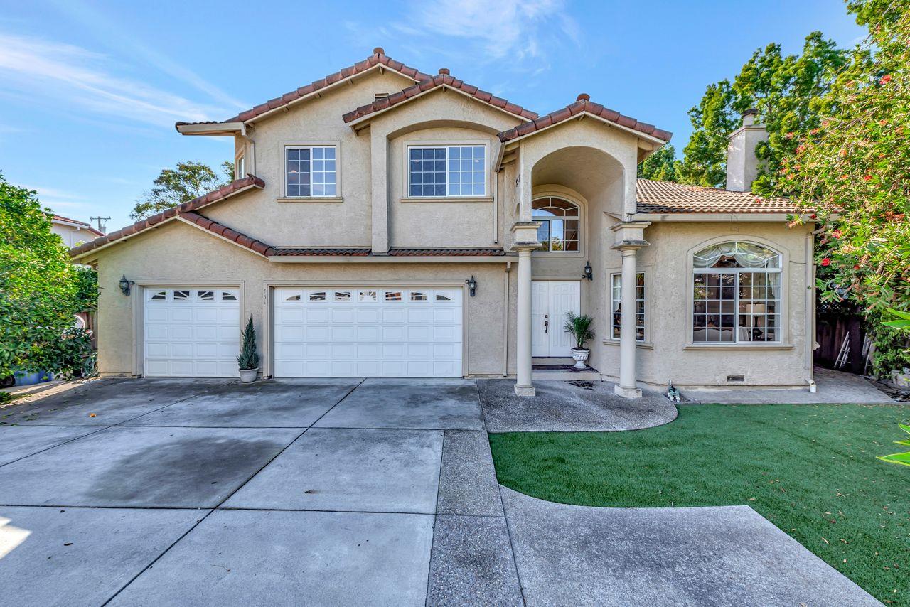 a view of a house with a yard plants and large tree