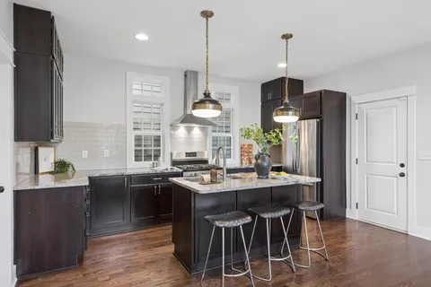 a kitchen with stainless steel appliances granite countertop a sink a stove and a wooden floors