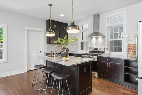 a kitchen with a sink stove and wooden floor