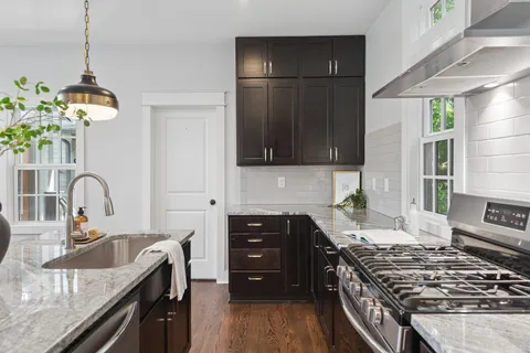 a kitchen with stainless steel appliances granite countertop a stove a sink dishwasher and a refrigerator with wooden floor