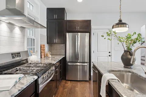 a kitchen with stainless steel appliances granite countertop a refrigerator a stove and a sink