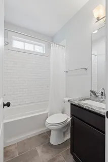 a bathroom with a granite countertop bathtub shower sink vanity and toilet
