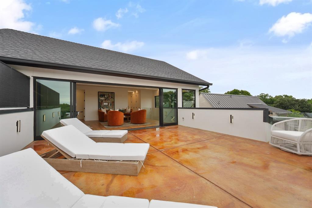 9457 Waterview Road Dallas, TX 75218 - Photo 25 of 25 Expansive rooftop deck featuring stained concrete flooring, a partial privacy wall with integrated lighting, and direct access to an interior space through large sliding glass doors