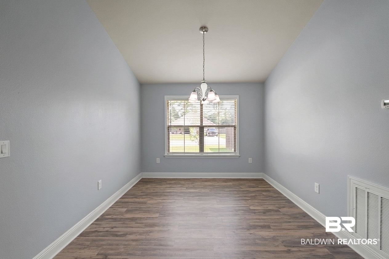 22076 Garland Loop Silverhill, AL 36576 - Photo 10 of 27 Spacious room featuring wood-finish flooring, light blue walls, white baseboards, and a single window with blinds
