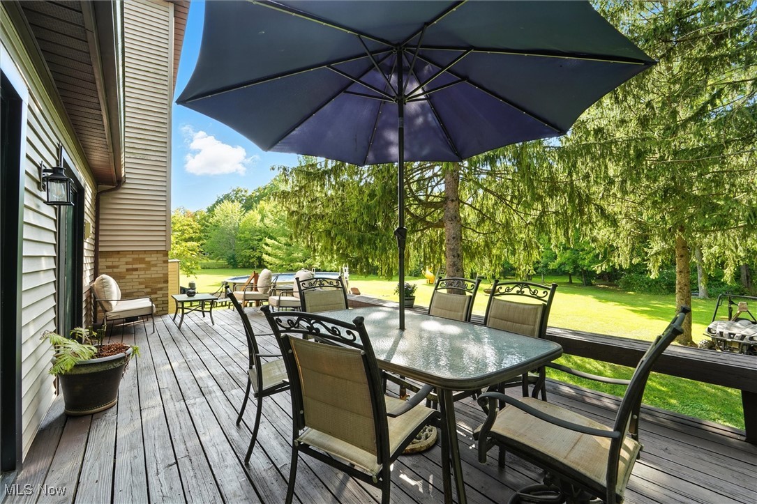 12120 Caves Road Chesterland, OH 44026 - Photo 19 of 50 Wooden terrace with outdoor dining space, a lawn, and view of wooded area