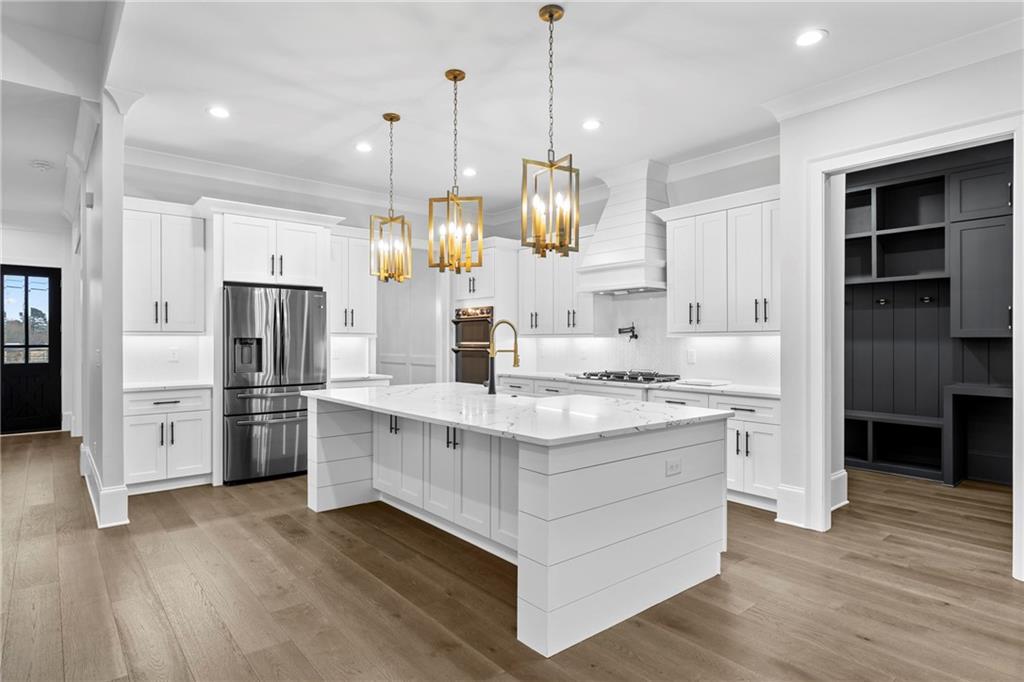 2381 Jones Phillips Road Dacula, GA 30019 - Photo 11 of 57 a kitchen with stainless steel appliances granite countertop a sink stove a refrigerator and a kitchen island with wooden floor