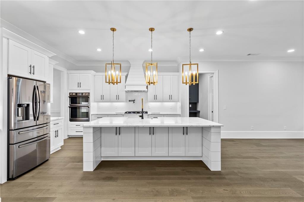2381 Jones Phillips Road Dacula, GA 30019 - Photo 13 of 57 a large white kitchen with wooden floor and stainless steel appliances