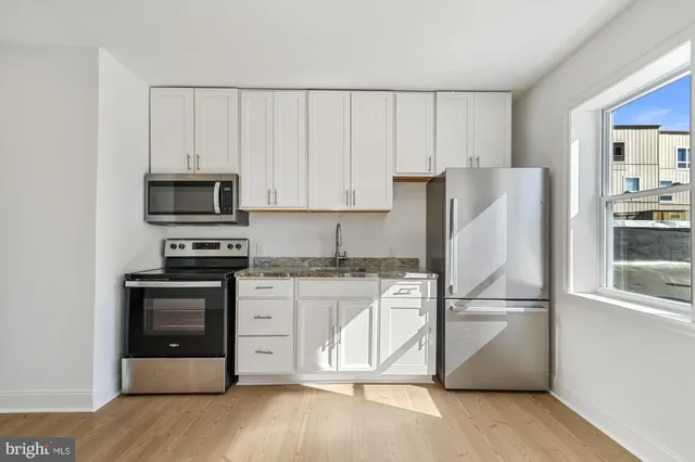 a kitchen with granite countertop white cabinets and stainless steel appliances