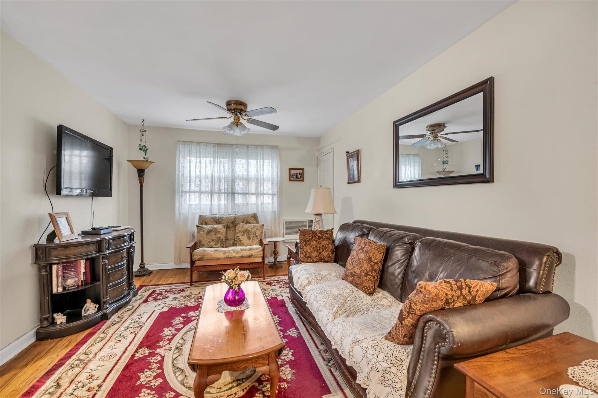 69-18 Bell Boulevard, Unit B Queens, NY 11364 - Photo 2 of 9 a living room with furniture and a flat screen tv