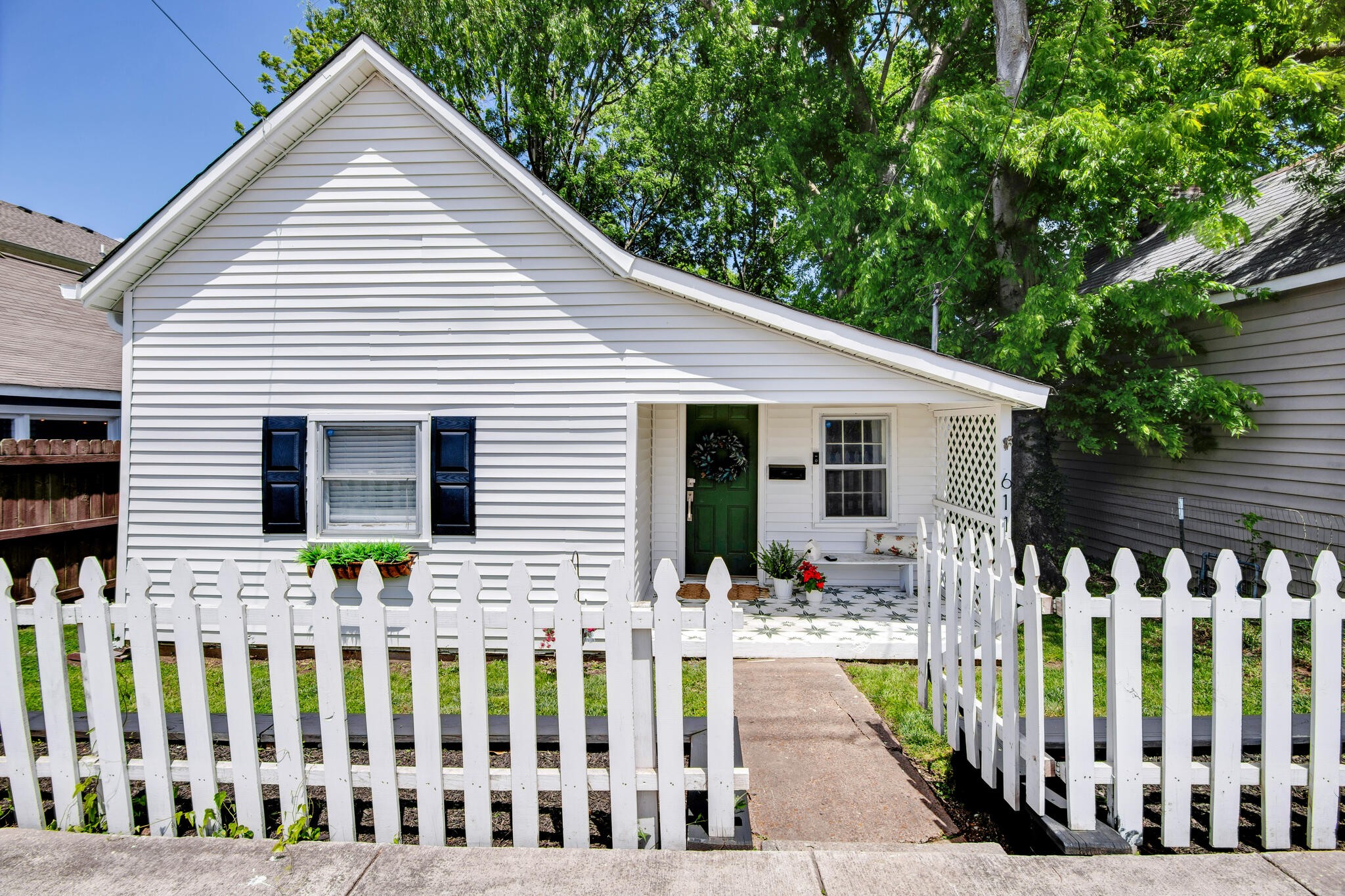 a view of a house with wooden porch next to a yard
