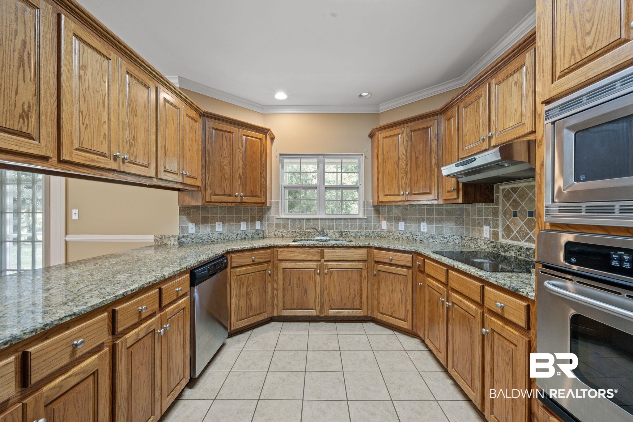 5618 Leytham Road Theodore, AL 36582 - Photo 21 of 60 Kitchen with stainless steel appliances, light stone counters, light tile patterned floors, decorative backsplash, and crown molding