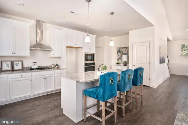a kitchen with stainless steel appliances granite countertop a refrigerator a stove a sink dishwasher and white cabinets with wooden floor