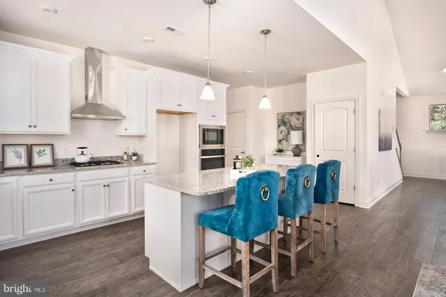 a kitchen with stainless steel appliances granite countertop a refrigerator a stove a sink dishwasher and white cabinets with wooden floor