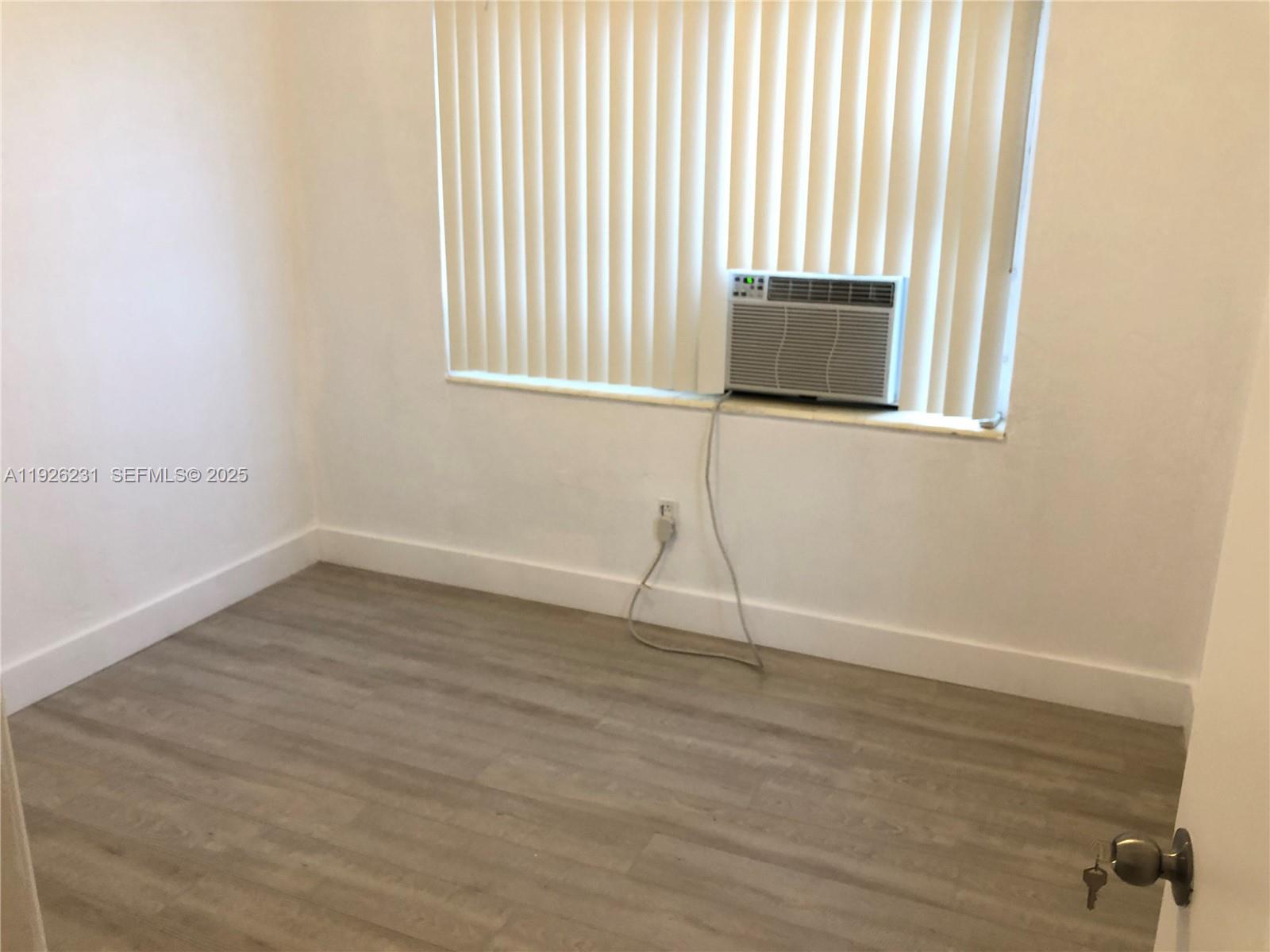 8340 Crespi Boulevard, Unit 19 Miami Beach, FL 33141 - Photo 18 of 35 an empty room with wooden floor and windows