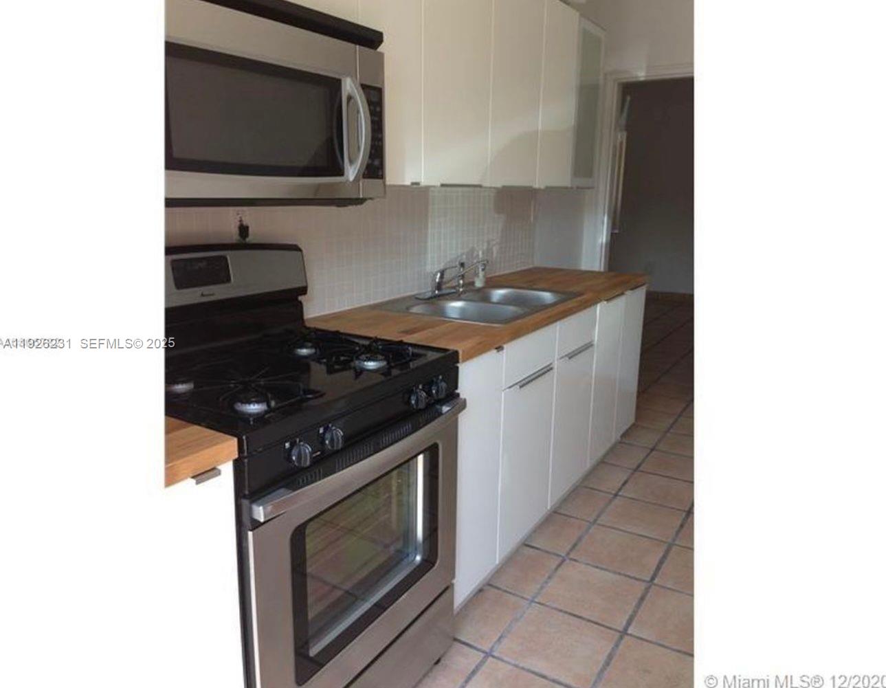 8340 Crespi Boulevard, Unit 19 Miami Beach, FL 33141 - Photo 33 of 35 a kitchen with a stove and a microwave