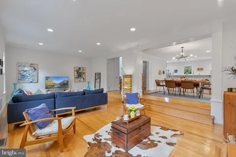 a living room with furniture and a dining table with wooden floor