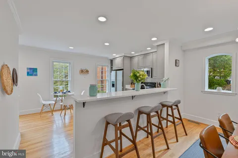 a kitchen with stainless steel appliances kitchen island granite countertop a dining table chairs and white cabinets