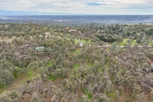an aerial view of residential houses with outdoor space and trees