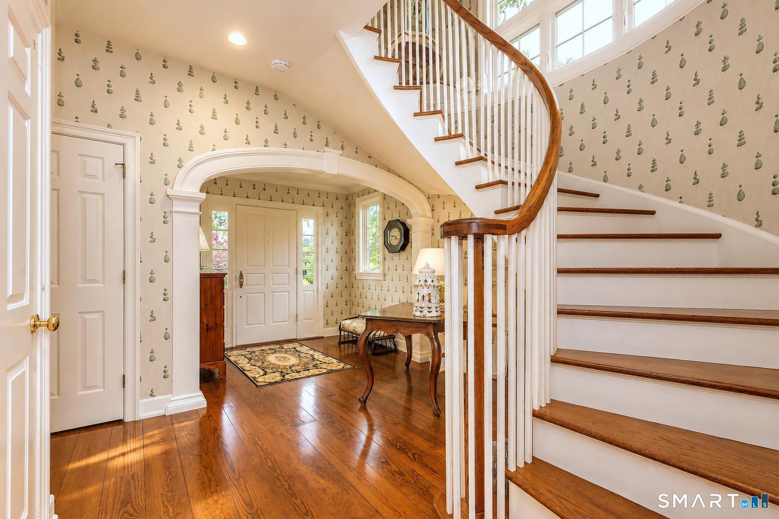 1681 Fairfield Beach Road Fairfield, CT 06824 - Photo 7 of 36 The journey begins here, where a sweeping staircase, arched openings, and natural light introduce the architectural rhythm that defines the home throughout.
