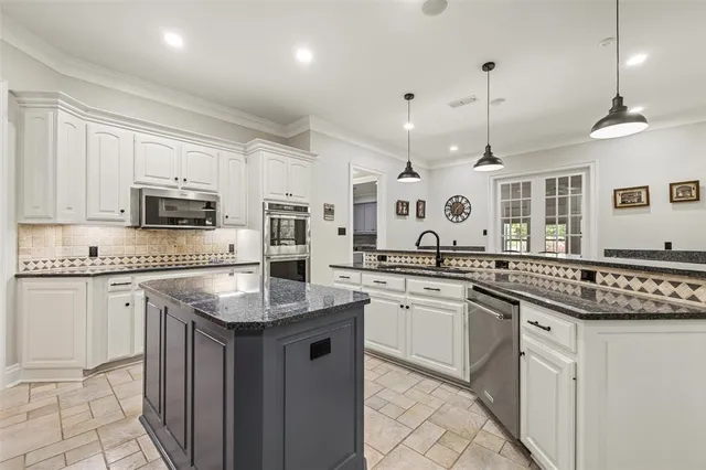 a kitchen with stainless steel appliances granite countertop a sink and stove a oven with white cabinets