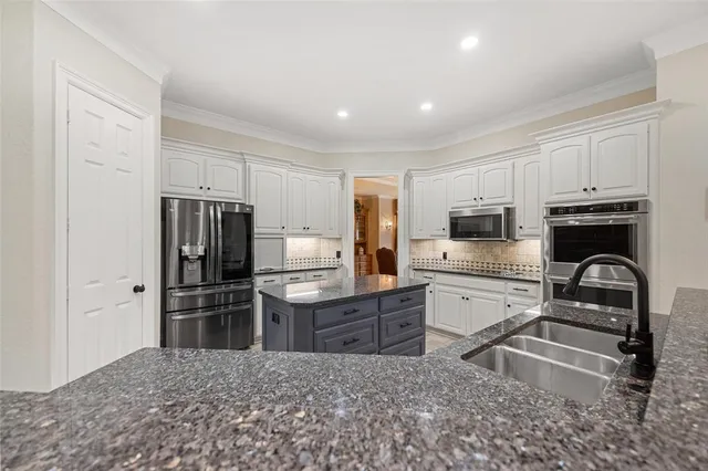 a kitchen with granite countertop a refrigerator and a stove top oven